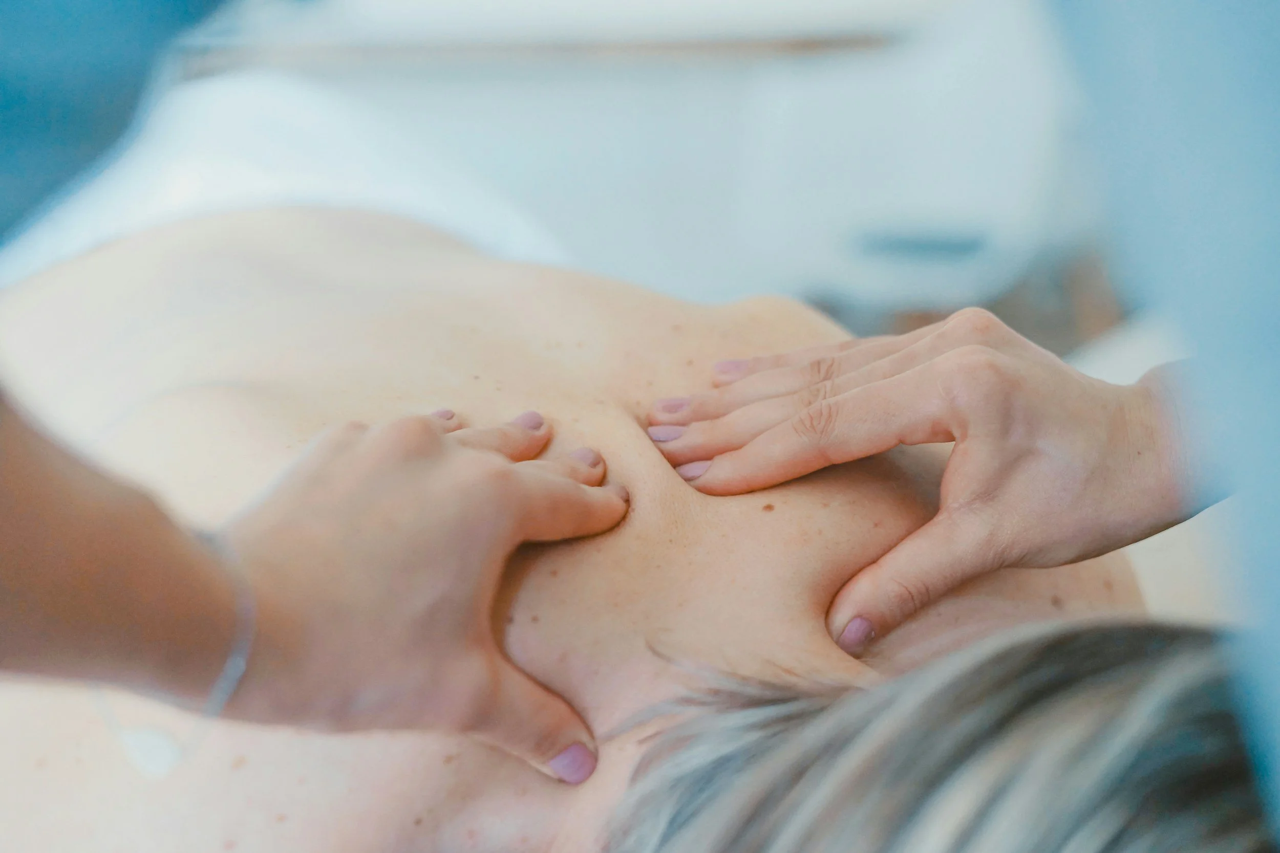 Close-up of a person receiving a back massage from a therapist.